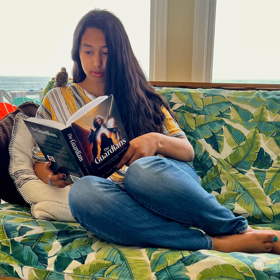 Young woman on couch reading The Guardians book